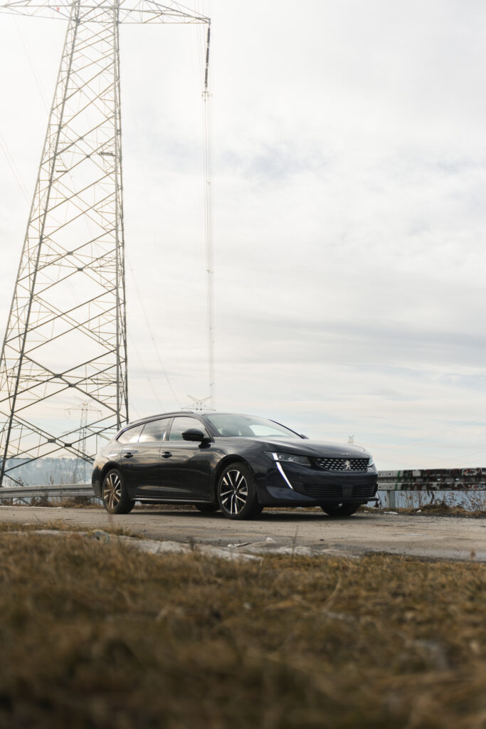 Niskie ujęcie czarnego Peugeota obok stalowego słupa energetycznego, Fotograf Skawina.
