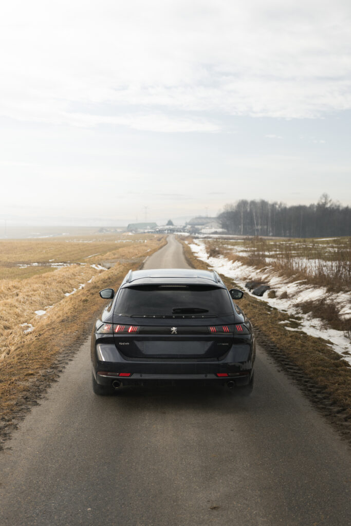 Tył czarnego Peugeota 508 na wąskiej drodze wśród pól, profesjonalny fotograf Skawina.