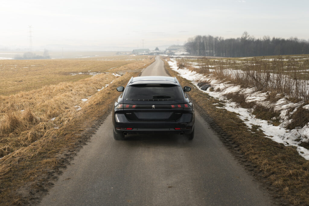 Czarny samochód na drodze w zimowym krajobrazie, widok od tyłu, fotografia motoryzacyjna.