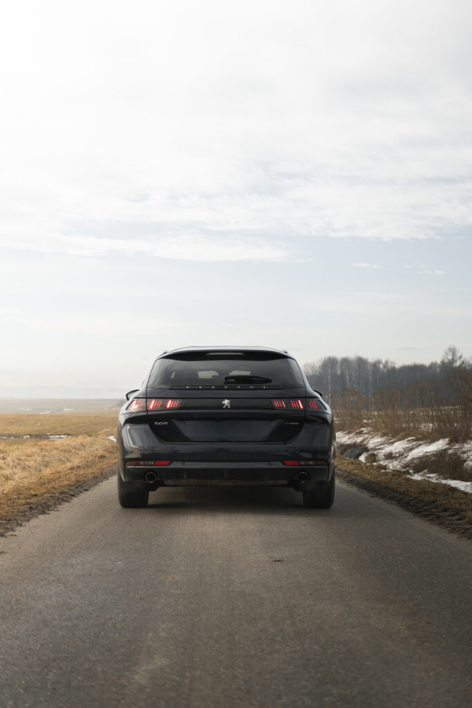 Niskie ujęcie tyłu ciemnego auta na drodze asfaltowej, niebo w tle, fotograf.