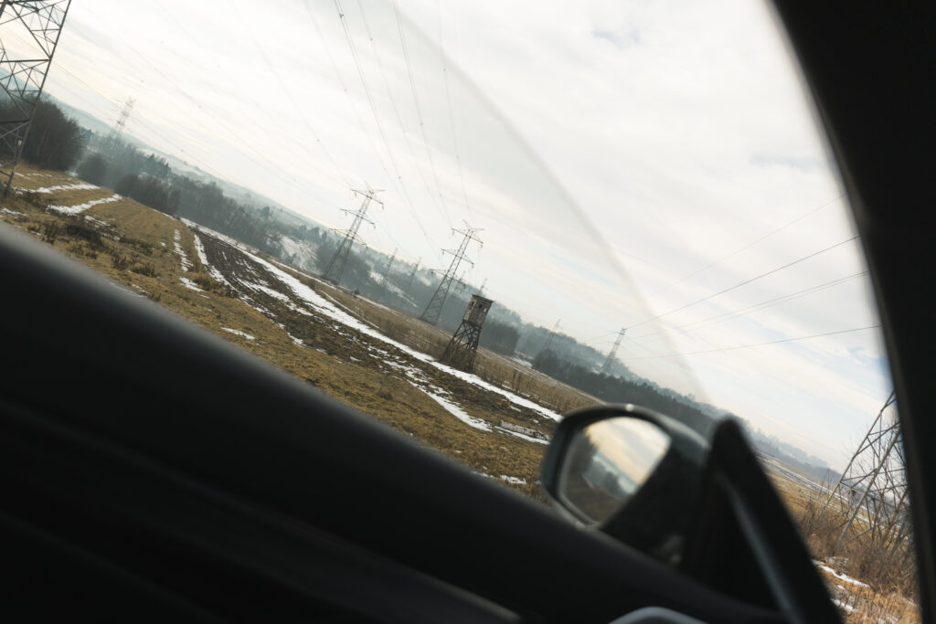 Widok z okna samochodu na wieżę obserwacyjną i linie energetyczne, fotografia krajobrazowa.